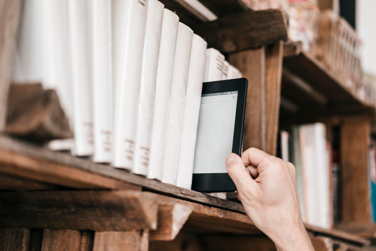 Hand taking e-book from book shelf - stock photo