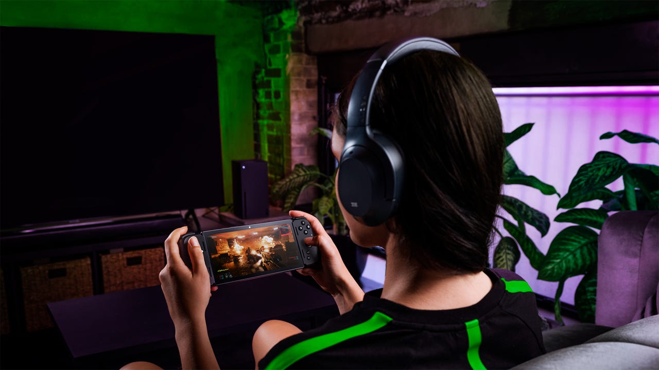 A woman playing Razer's Edge gaming portable in a dark living room
