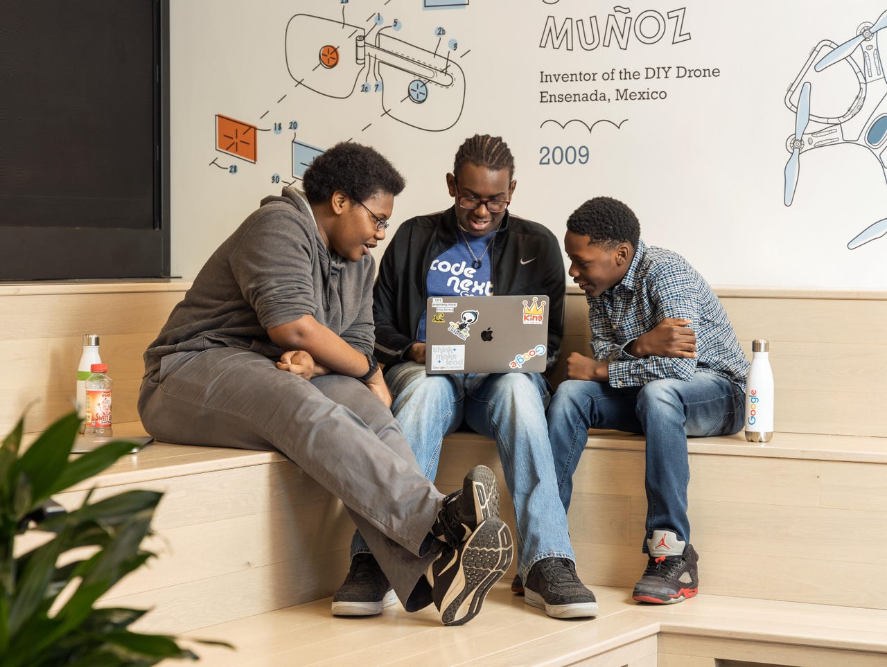 Three students share a table and laptops at Google's Code Next lab.