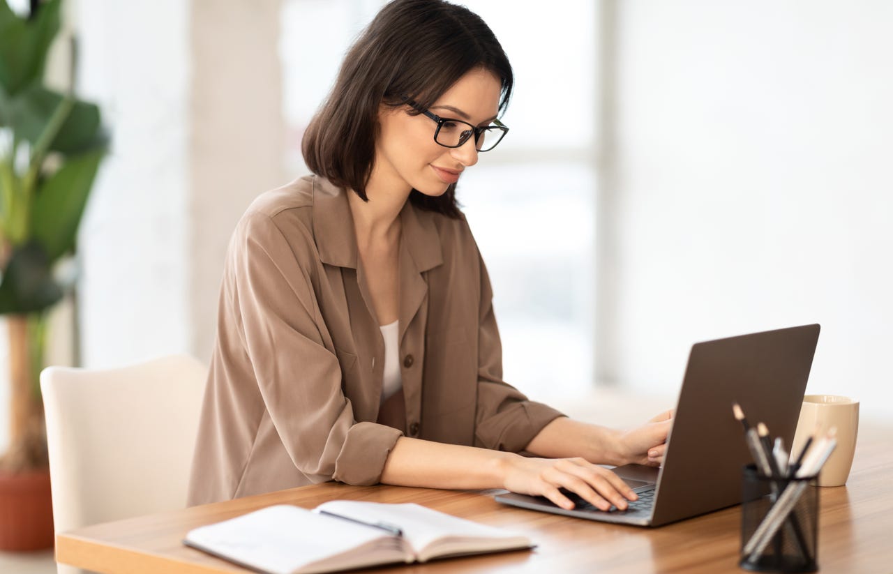 Woman typing on laptop in a bright office setting