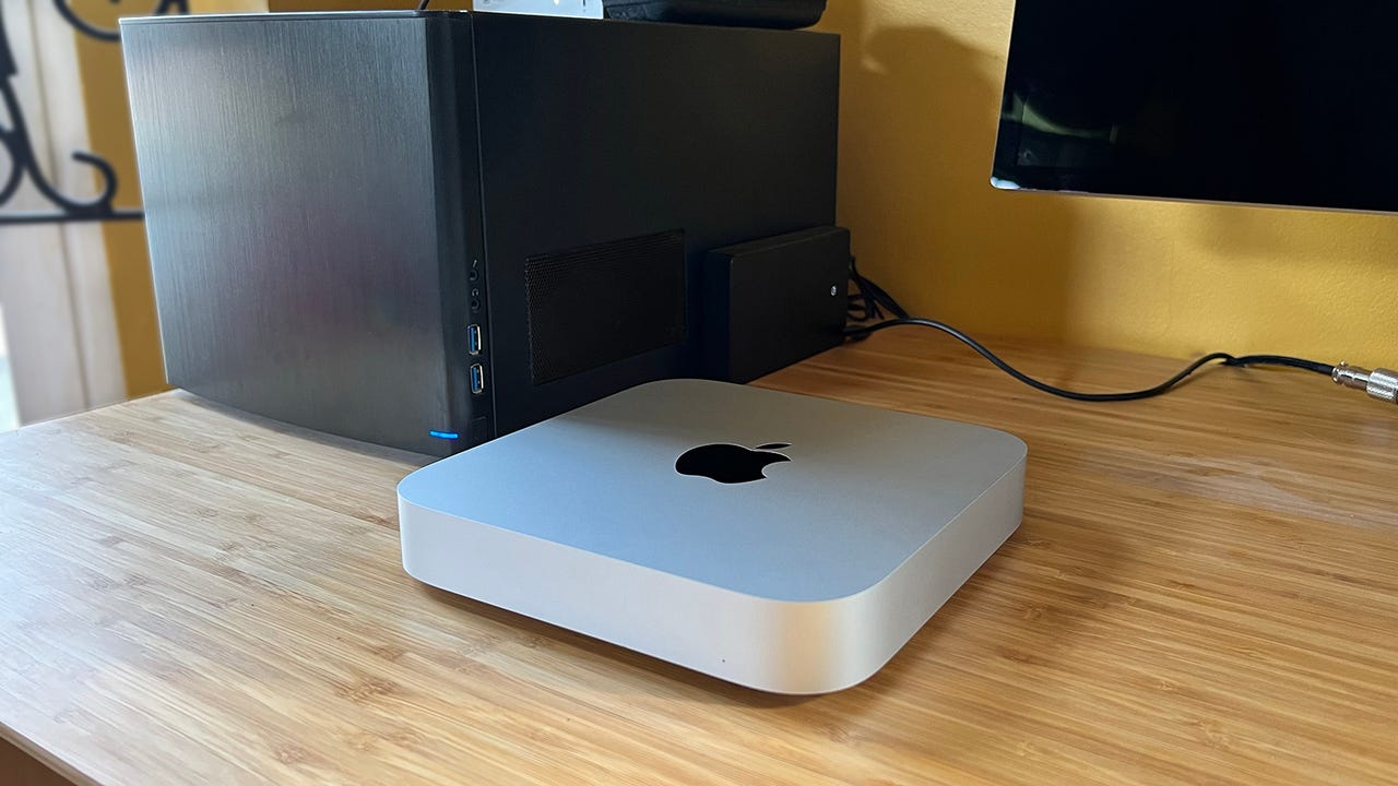 An Apple M2 Mac Mini sitting next to a small form factor PC