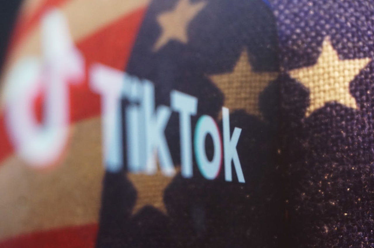 Logotipo de TikTok en un teléfono inteligente contra una bandera estadounidense