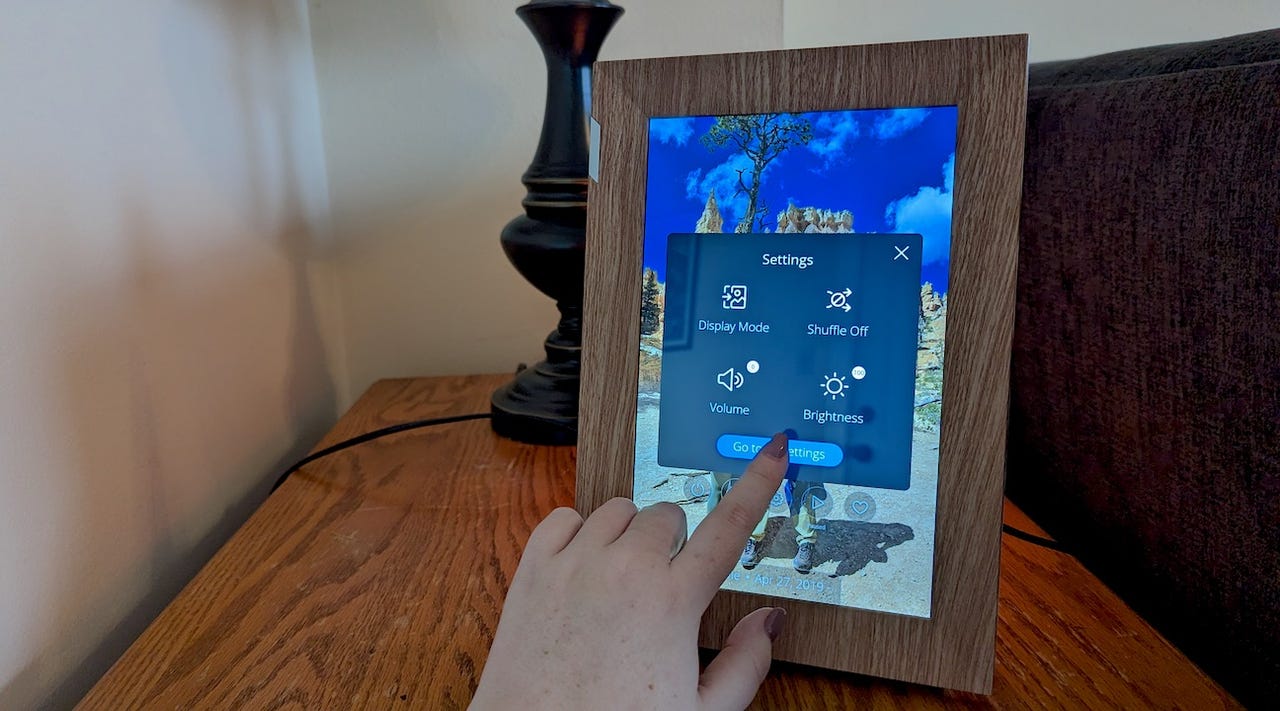 Person's hand touching the screen of a Nixplay digital photo frame