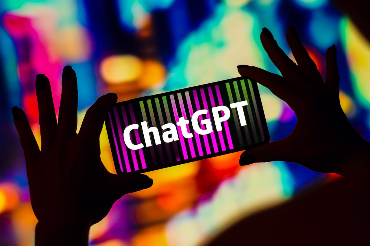 Hands holding phone that says ChatGPT silhouetted against colorful background