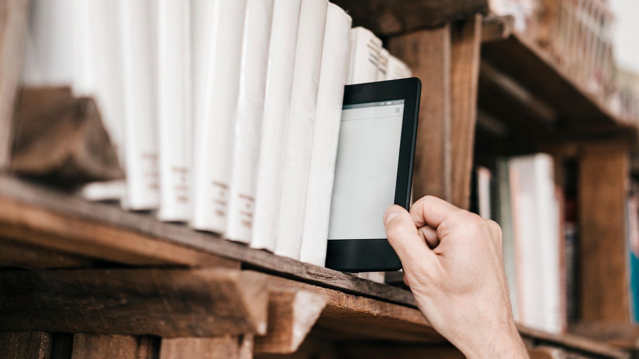Hand taking e-book from book shelf - stock photo